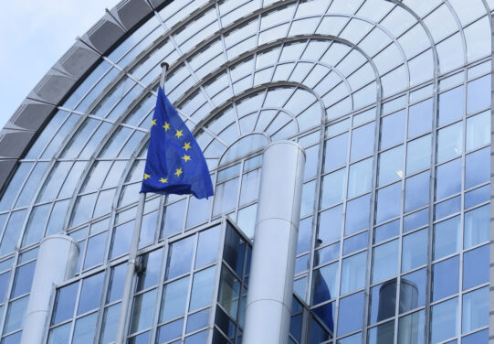 EU parlamentin lasinen julkisivu ja EU:n lippu.