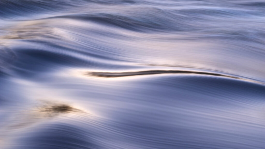 a blue-violet water surface on which light forms shadows and highlights.