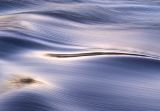 a blue-violet water surface on which light forms shadows and highlights.